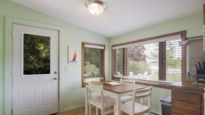 Ein Zimmer mit Esstisch und Stühlen, einer weißen Tür und Fenstern mit Jalousien.