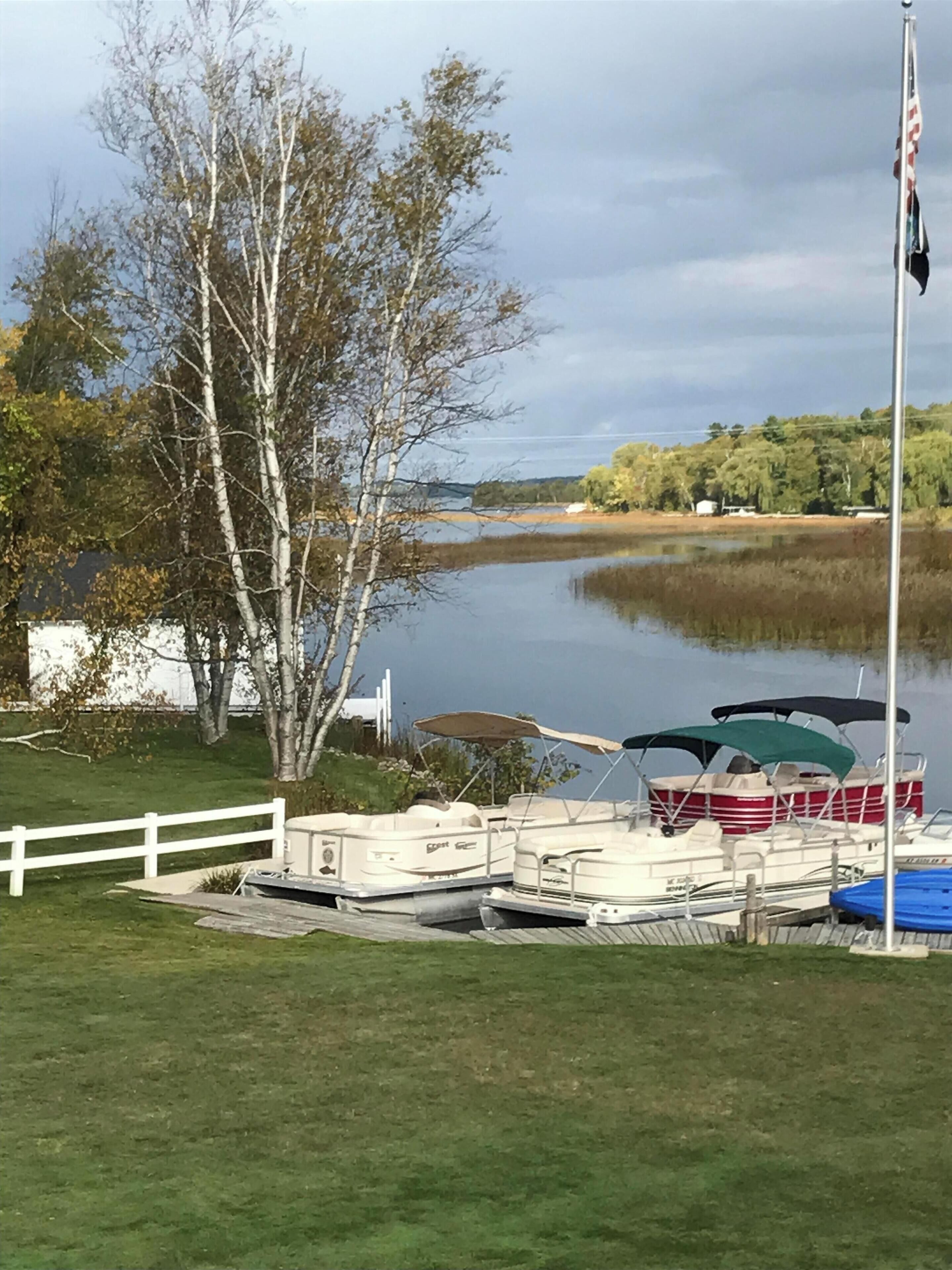 Une vue sur le lac, avec des bateaux amarrés, un mât et une clôture blanche.