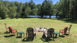 A grassy area with a fire pit and Adirondack chairs. - Secluded / Private Maine Lake Retreat,
WIR SPRECHEN DEUTSCH , (Burnham)