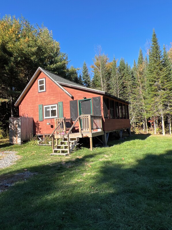 Une cabane rouge avec une terrasse en bois et un escalier menant à un porche.