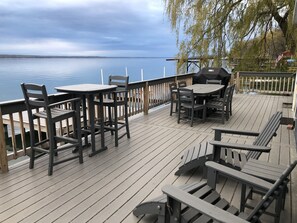 Una terraza de madera con mesas y sillas, con vista a un lago tranquilo.