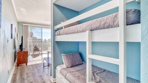 A room with bunk beds, a balcony with a view, and a desk with a chair. - Gulf Place Cabanas 307 - Access to Pool (Santa Rosa Beach)