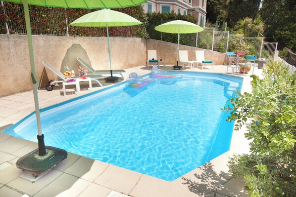 A swimming pool with lounge chairs and umbrellas.