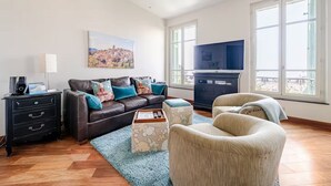 Un salon avec un canapé, une table basse, un téléviseur et un tableau accroché au mur.
