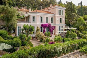 Un bâtiment à deux étages, doté d’un jardin à l’avant, avec un escalier menant à l’entrée.