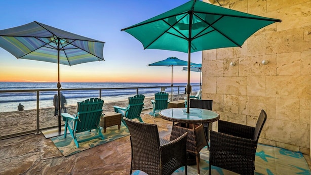 A terrace with outdoor seating, including chairs and tables, overlooking a beach. - OCEAN FRONT STUDIO ON THE SAND! (Carlsbad)