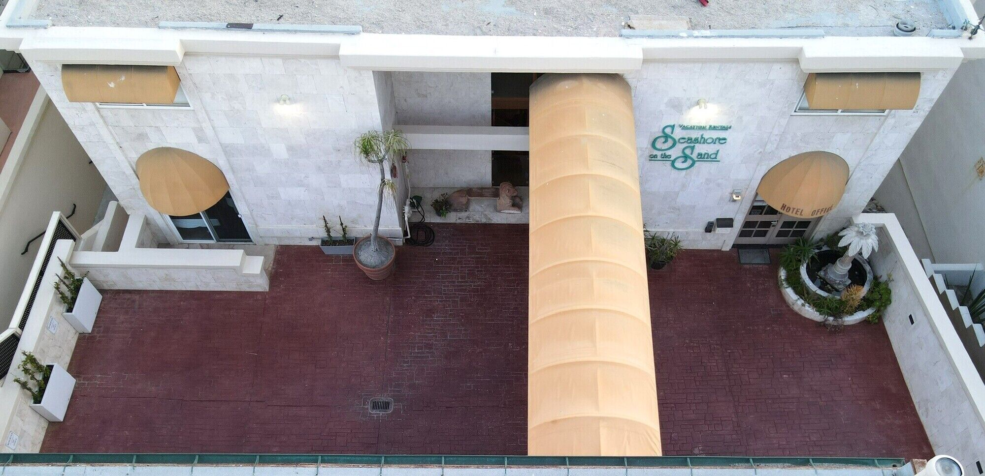 Fachada de hotel con un pilar central grande, dos pilares laterales y un letrero que dice "Scashore on the Sand".