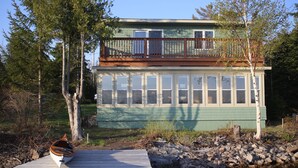 Ein zweistöckiges Haus mit einer Terrasse und einem Steg.
