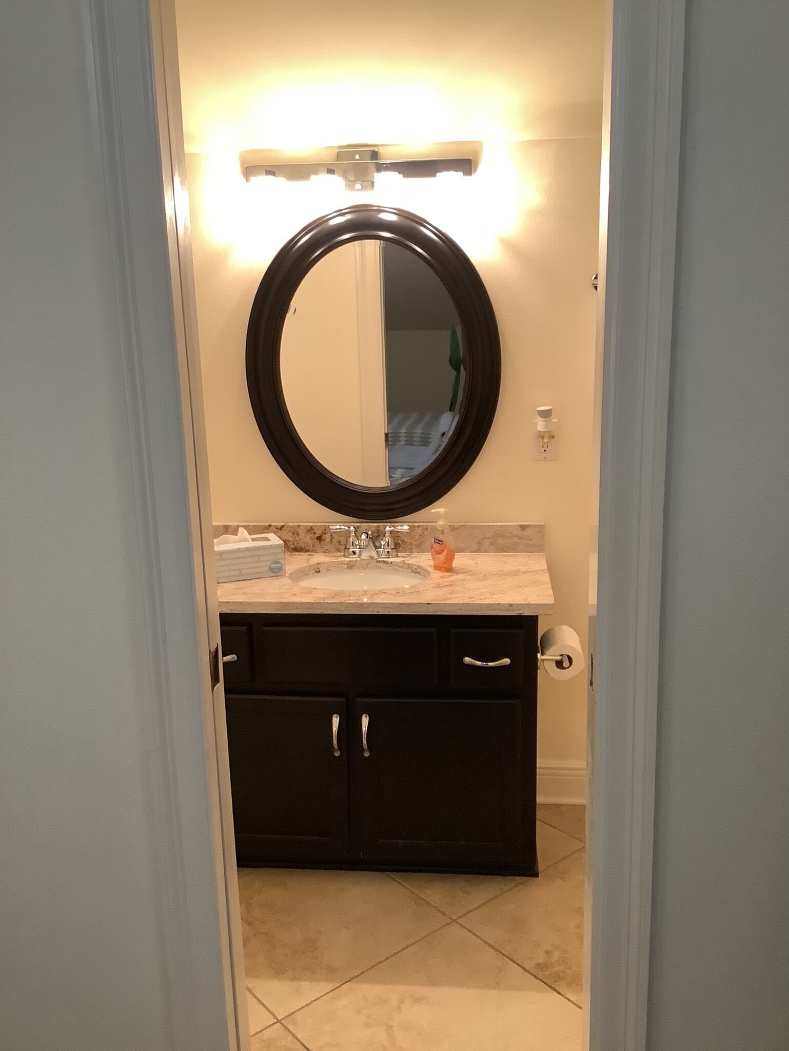 A bathroom with a round mirror, a sink, and a toilet.