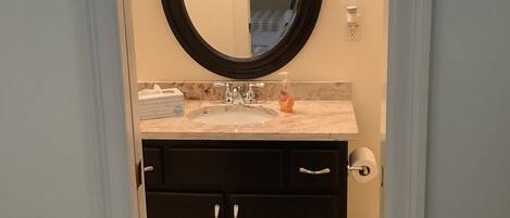 A bathroom with a round mirror, a sink, and a toilet.