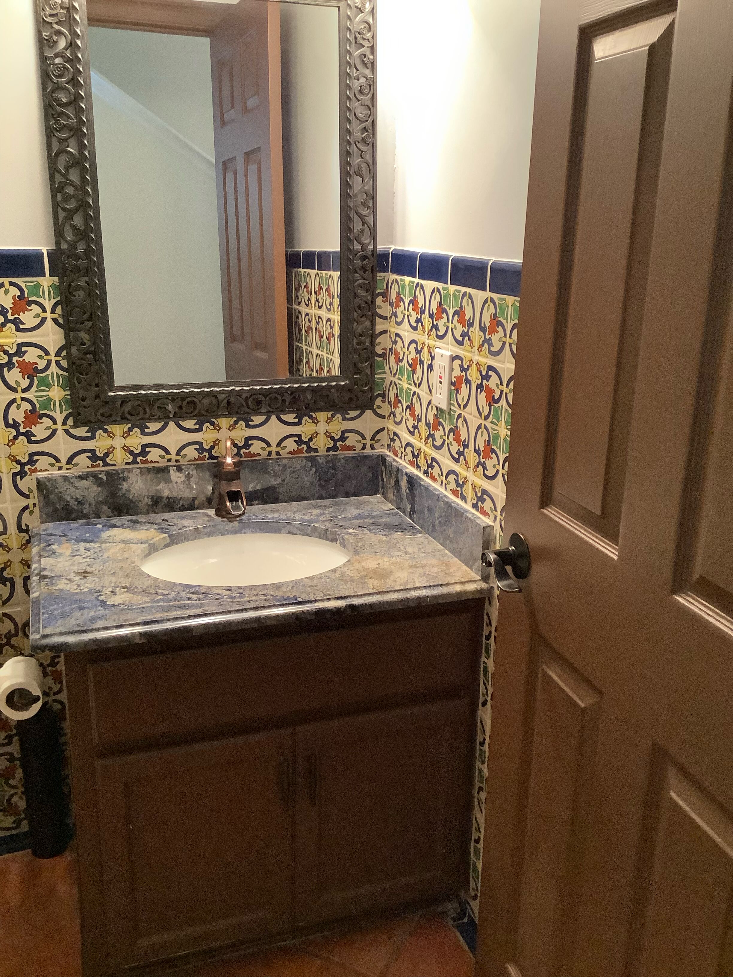Un baño con lavabo, espejo y paredes con azulejos.