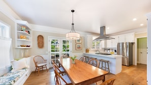 A spacious kitchen with a wooden dining table, white cabinetry, and a stainless steel refrigerator. - Charming Farm House Downtown St. Helena!  3bedrooms/3baths
Permit # STR26-014 (St Helena)
