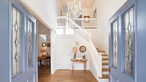 A staircase with white railings leading to an upper floor, a wooden floor, and a door with decorative glass panels. - Charming Farm House Downtown St. Helena!  3bedrooms/3baths
Permit # STR26-014 (St Helena)