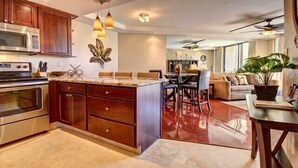 A modern kitchen with a central island, stainless steel appliances, and pendant lighting. - Premier Ocean View! King Luxury Bed, A/C, Clean, Cozy, Updated, Wifi, Beach Gear (Kihei)