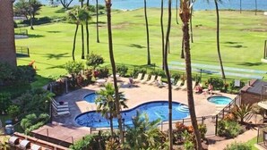 A pool area with two pools, palm trees, and a view of the ocean. - Premier Ocean View! King Luxury Bed, A/C, Clean, Cozy, Updated, Wifi, Beach Gear (Kihei)