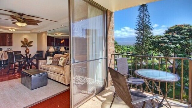 A balcony with a glass door, a dining area with a table and chairs, and a sofa. - Premier Ocean View! King Luxury Bed, A/C, Clean, Cozy, Updated, Wifi, Beach Gear (Kihei)