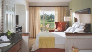 Une chambre d’hôtel équipée d’un lit, d’un bureau, d’une chaise, d’une télévision et d’une fenêtre donnant sur un terrain de golf.
