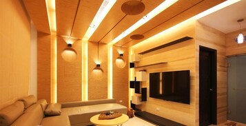 Una sala de estar moderna con techo de madera, televisor empotrado y un área de descanso acogedora.