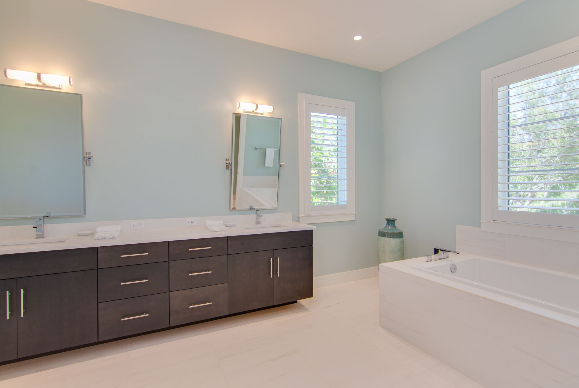 Une salle de bain moderne avec un meuble-lavabo foncé, un grand miroir et une baignoire.