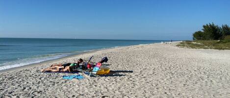 Ranta lähistöllä, aurinkotuoleja, rantapyyhkeitä