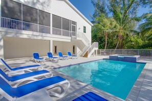 Relax by the pool surrounded by lush greenery and palm trees.