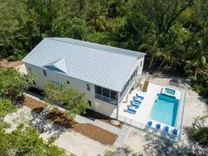 Situated in a lush tropical setting, this house features a large swimming pool surrounded by a deck area with lounge chairs.