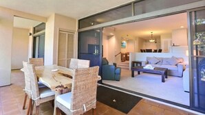 Un espace de vie moderne comprenant une table à manger, des chaises en osier, un canapé et une table basse.