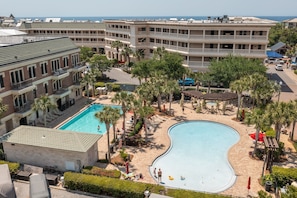A resort with a large swimming pool, multiple buildings, and palm trees.