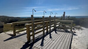 Una terrassa de fusta amb barana, amb vista a una platja i l'oceà.