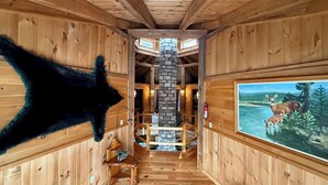 A wooden interior with a stone fireplace, wooden benches, and a painting of deer. - UNFORGETTABLE TIMES...500+ ACRES, 3/4 MILE ON PINE CREEK! (Gaines)