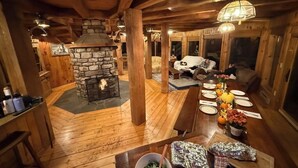 A cozy cabin interior with a stone fireplace, wooden floors, and a dining area set for a meal. - UNFORGETTABLE TIMES...500+ ACRES, 3/4 MILE ON PINE CREEK! (Gaines)