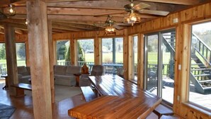 A wooden interior with a large dining table, benches, and a sofa. - UNFORGETTABLE TIMES...500+ ACRES, 3/4 MILE ON PINE CREEK! (Gaines)