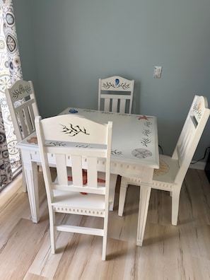 Mesa de jantar com cadeiras, cortina estampada e parede azul claro.