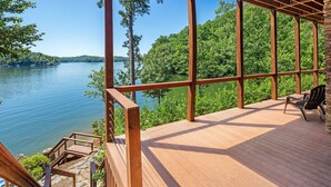 Eine Holzterrasse mit Blick auf einen See und einen Wald.