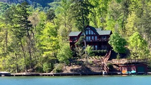Eine Hütte mit Balkon, umgeben von dichtem Wald und einem See.