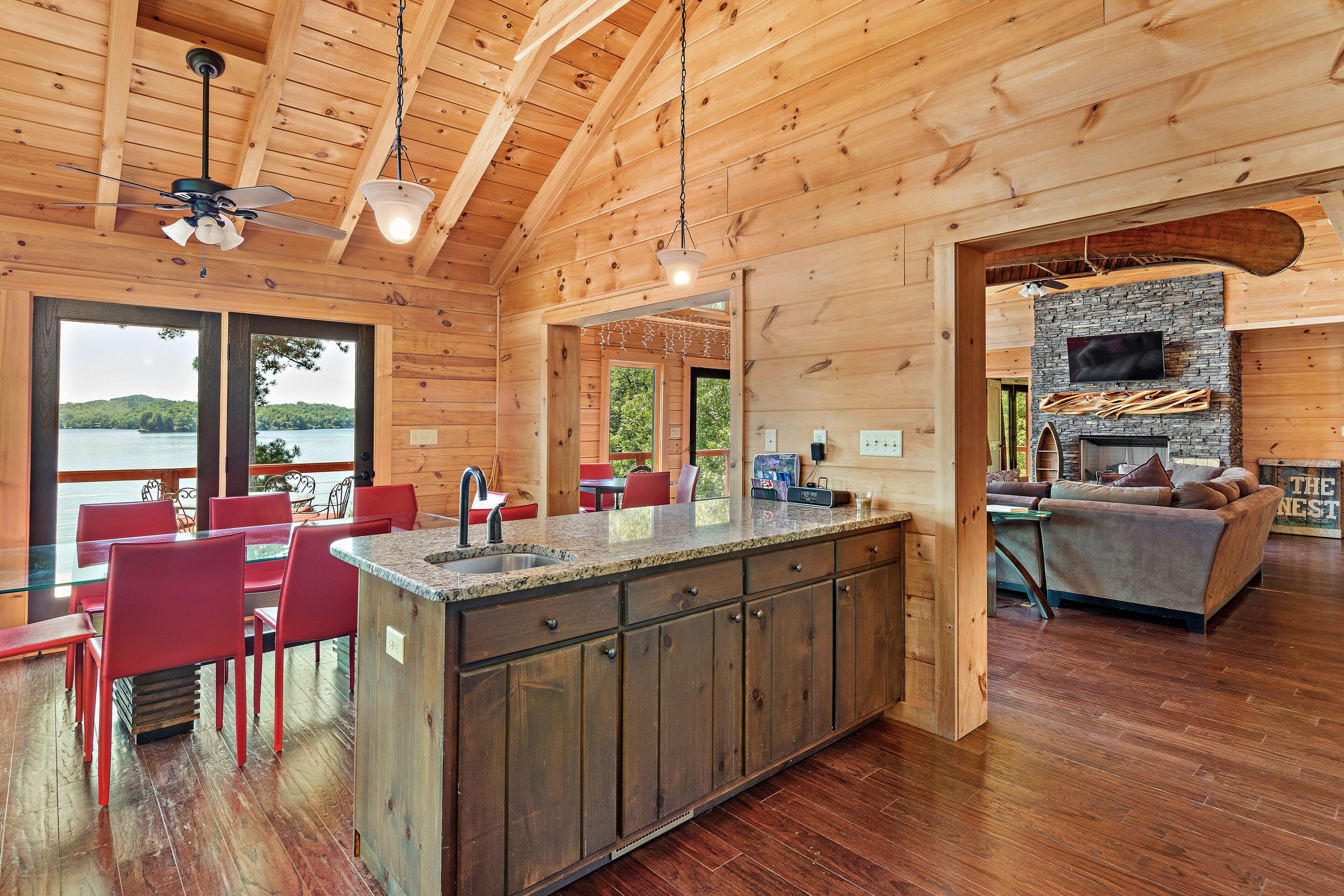 Una cabaña de madera espaciosa con una isla de cocina grande, comedor y sala de estar acogedora con chimenea.