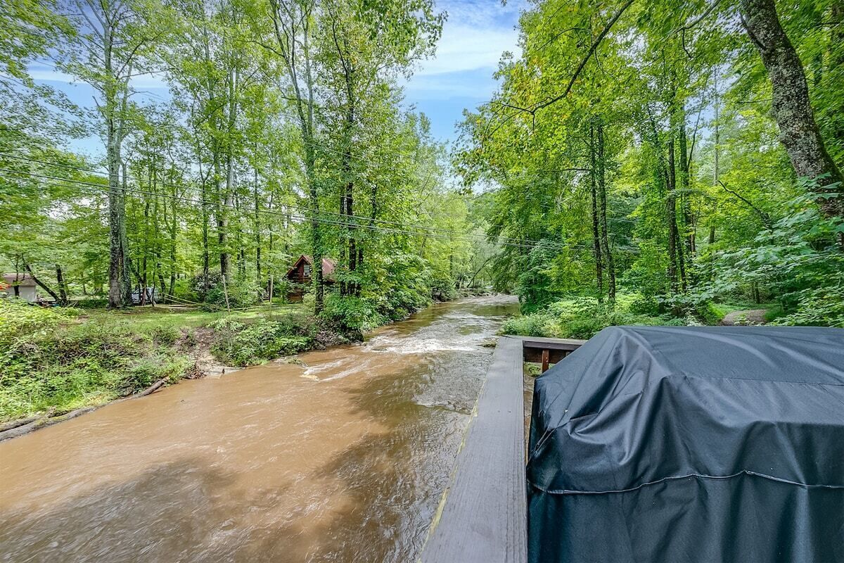 A river flowing through a forested area with a covered outdoor seating area.