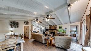 A spacious living room with a high ceiling, wooden floors, and a dining area with a table and chairs. - River's Edge - Ultimate Riverfront Cabin w/Hot Tub (Helen)