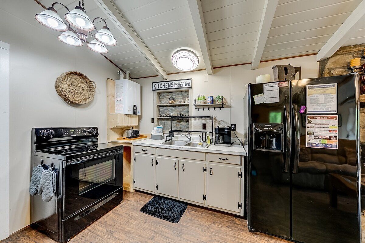 A kitchen with a black stove, white cabinets, and a black refrigerator.