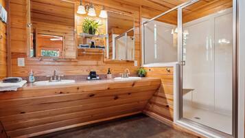 A wooden cabin-style bathroom with a large sink, mirror, and shower area.