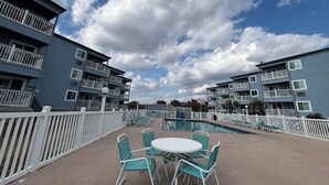 A pool area with a white fence, a pool, and several lounge chairs. - Oceanfront Condo • 2026 Renovations! • 2 BD, 2BA (Myrtle Beach)