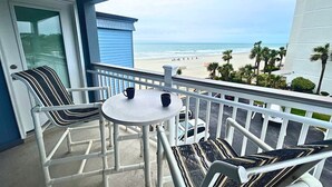 A balcony with a view of the beach, a white car, and a blue building. - Oceanfront Condo • 2026 Renovations! • 2 BD, 2BA (Myrtle Beach)