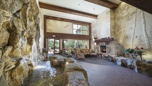 A spacious lobby with a waterfall feature, stone walls, and a fireplace. - Family Friendly in River Run. Heated pool & slide, steps from gondola and shops (Keystone)
