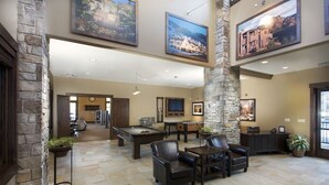 A spacious lobby with a pool table, comfortable seating, and stone accents.