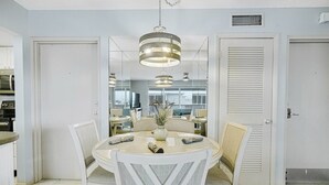 Un espace repas avec une table ronde, des chaises blanches et un luminaire suspendu.