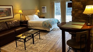 Ein Hotelzimmer mit einem Bett, einem Ledersofa, einem kleinen Tisch, einem Schreibtisch und einer Wand mit Steinverkleidung.
