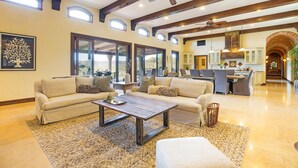 A spacious living room with a large sofa, a coffee table, and a fireplace. There are multiple windows and a view of the outdoors. - Farm Stay Villa on 55 Acres // Pool, Hot Tub & Complimentary Wine Tasting (Healdsburg)