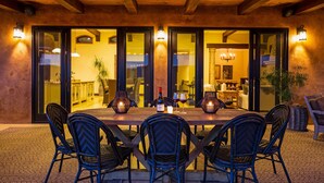 An outdoor dining area with a wooden table, four chairs, and two wall-mounted lights. - Farm Stay Villa on 55 Acres // Pool, Hot Tub & Complimentary Wine Tasting (Healdsburg)