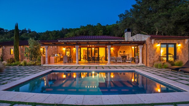 A poolside area with a stone house, outdoor seating, and a clear pool. - Farm Stay Villa on 55 Acres // Pool, Hot Tub & Complimentary Wine Tasting (Healdsburg)