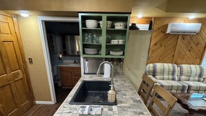 A kitchen with a central island, wooden cabinets, and a green shelving unit.